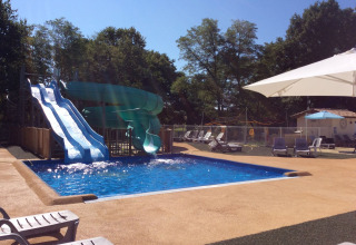 Outdoor swimming pool with waterslides and sun loungers at Campsite Les Franquettes in Nouvelle-Aquitaine, France.