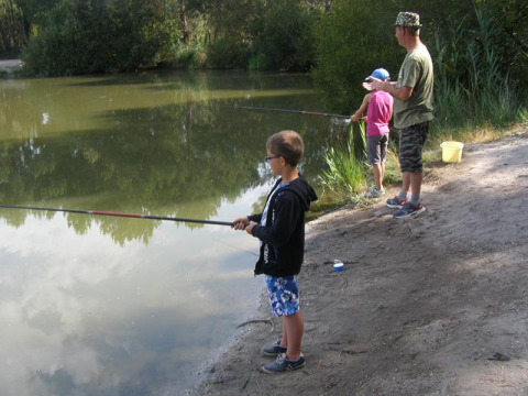 Una famiglia pesca insieme sulla riva del lago al campeggio Les Franquettes in Nouvelle-Aquitaine, Francia.