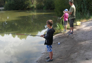 Una famiglia pesca insieme sulla riva del lago al campeggio Les Franquettes in Nouvelle-Aquitaine, Francia.