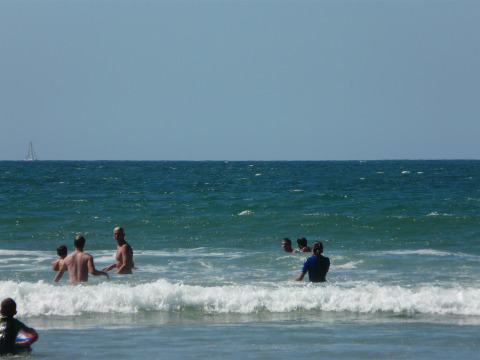 People swimming and playing in the waves at the beach near Grayan et l'Hôpital, Nouvelle-Aquitaine, France.