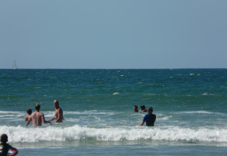 Persone che nuotano e giocano tra le onde sulla spiaggia vicino a Grayan et l'Hôpital, Nuova Aquitania, Francia.