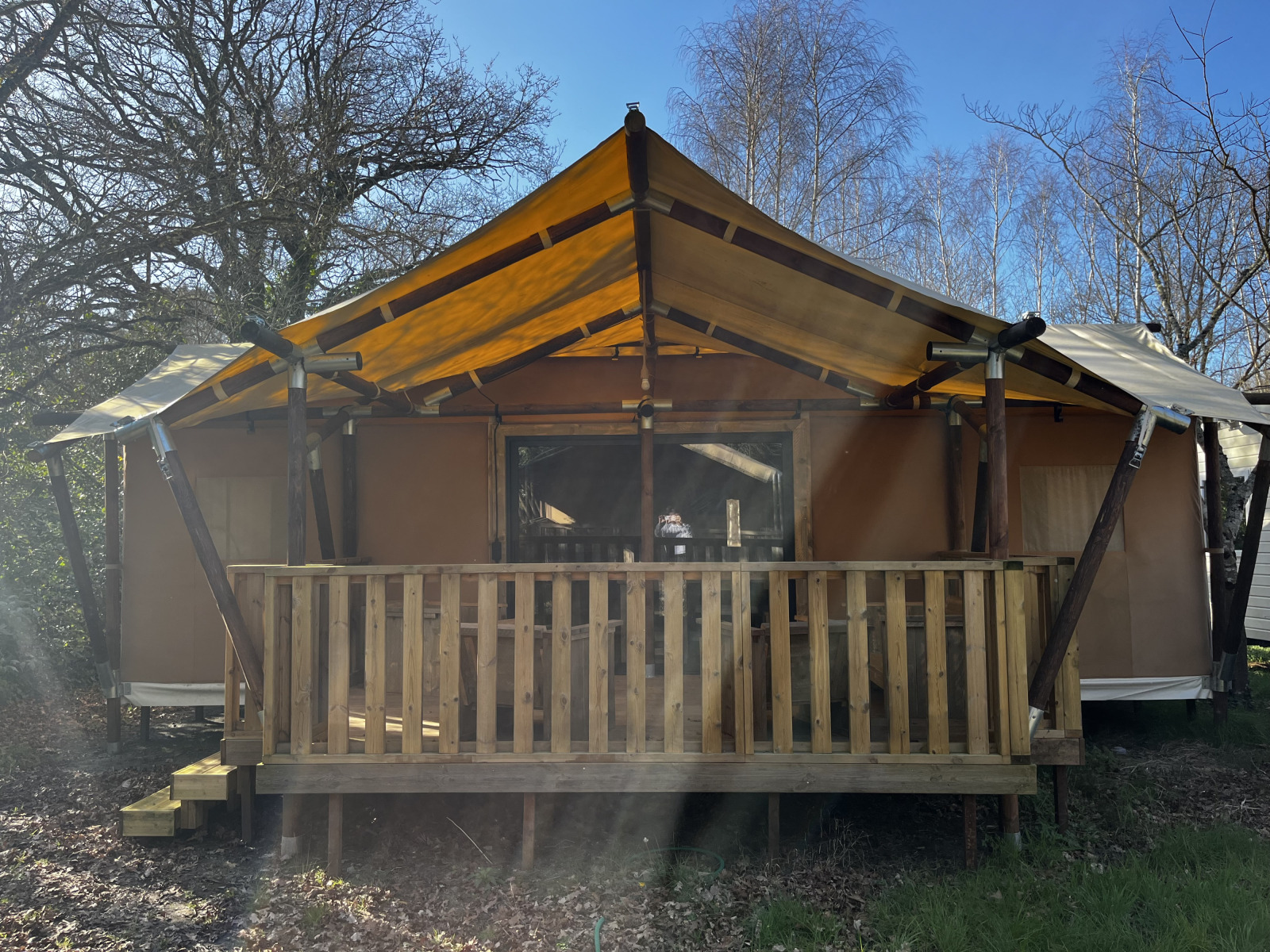 Foto van een safari tent Luxury Lodge XXL met ruime houten veranda en gele canvas overkapping.