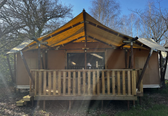 Foto di una tenda safari Luxury Lodge XXL con veranda in legno e tetto in tessuto giallo.