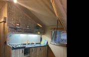 Vista interna di una cucina rustica all'interno di una tenda safari, Lodge Woody 27, al campeggio Les Franquettes in Francia.