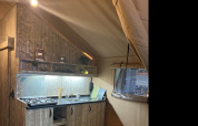 Vista interna di una cucina rustica all'interno di una tenda safari, Lodge Woody 27, al campeggio Les Franquettes in Francia.