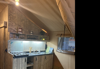 Vista interior de una cocina rústica dentro de una tienda safari, Lodge Woody 27, en el camping Les Franquettes en Francia.
