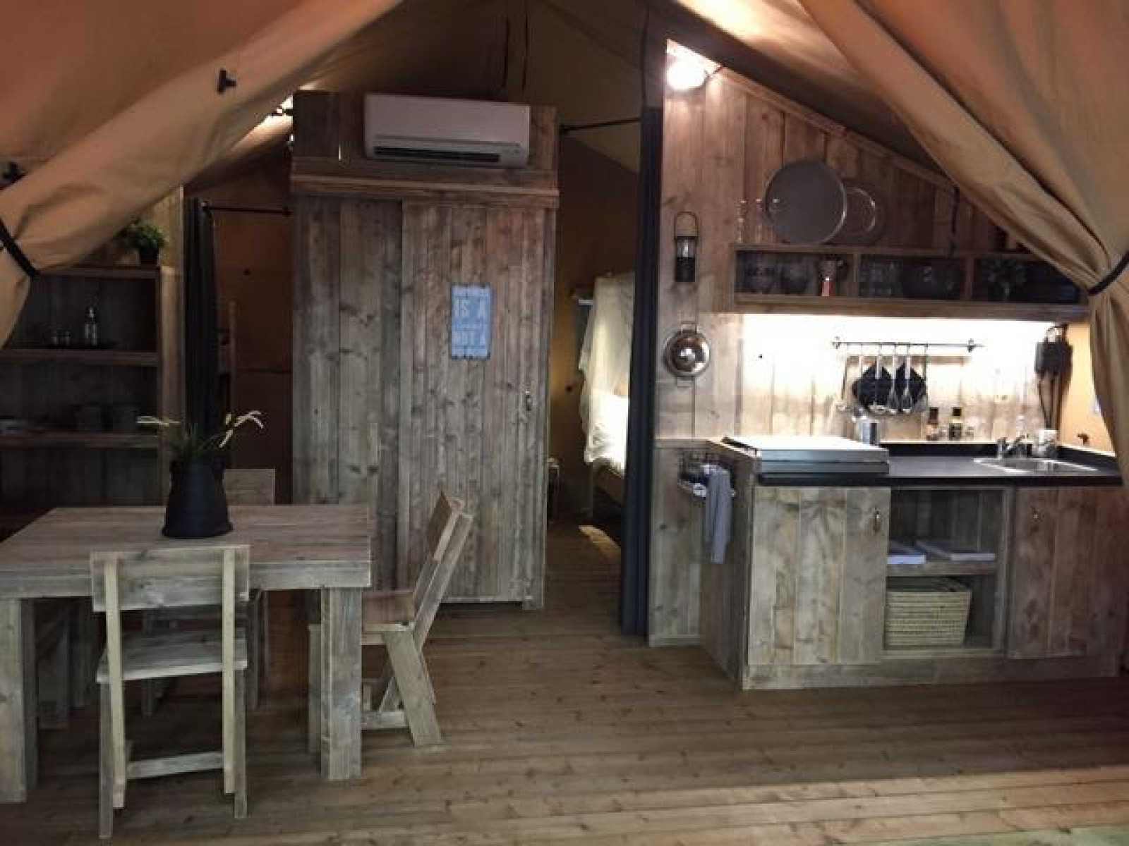 Interieur van het Lodge 'Woody 27' safaritent met houten meubels op Camping Les Franquettes in Frankrijk.