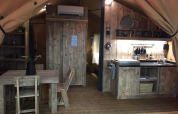 Interior view of Lodge 'Woody 27' safari tent with wooden furniture at Campsite Les Franquettes in France.