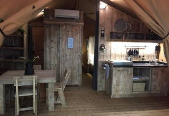 Vue intérieure du lodge safari « Woody 27 » avec mobilier en bois au camping Les Franquettes, en France.