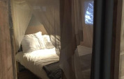 Interior of safari tent Lodge Woody 27 with mosquito net and bed at Campsite Les Franquettes, France.