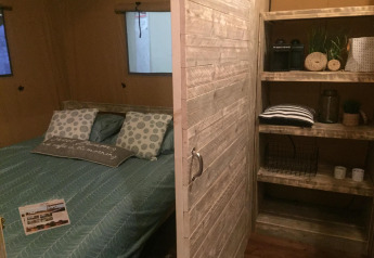 Innenansicht des Safarizelts Lodge Woody 38 auf Camping Les Franquettes in Frankreich mit Bett & Regal.