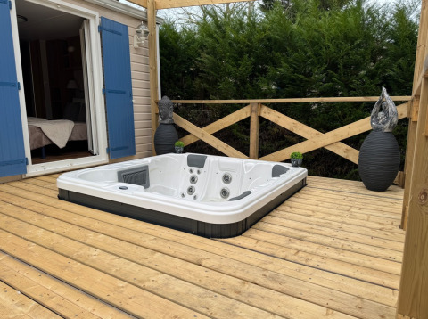 Udendørs træterrasse med indbygget spabad ved Premium Mobile Home, Campsite Les Franquettes, Frankrig.