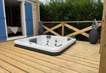 Holzterrasse mit eingelassenem Whirlpool am Premium Mobile Home, Campingplatz Les Franquettes in Frankreich.