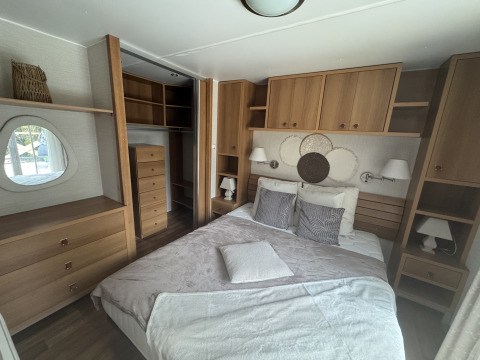 Premium Mobile Home-soveværelse på Camping Les Franquettes i Frankrig med dobbeltseng og træmøbler.