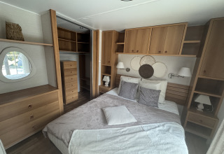 Premium Mobile Home-soveværelse på Camping Les Franquettes i Frankrig med dobbeltseng og træmøbler.