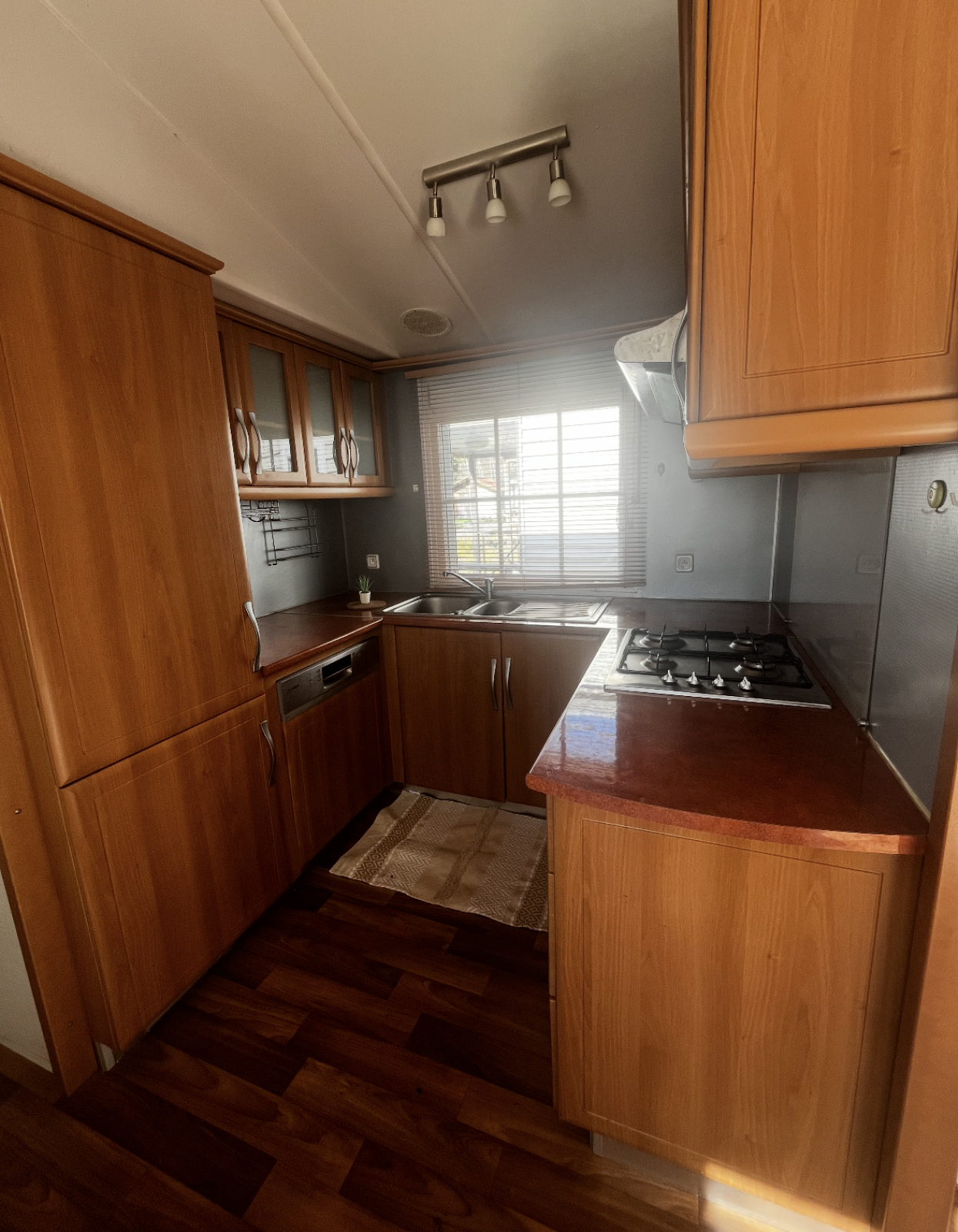 Keuken in Premium Mobile Home op Camping Les Franquettes in Frankrijk, met houten kasten en fornuis.