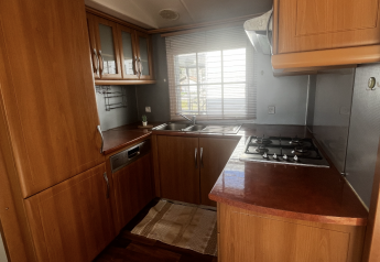 Cocina en Premium Mobile Home del Camping Les Franquettes en Francia, con armarios de madera y encimera.