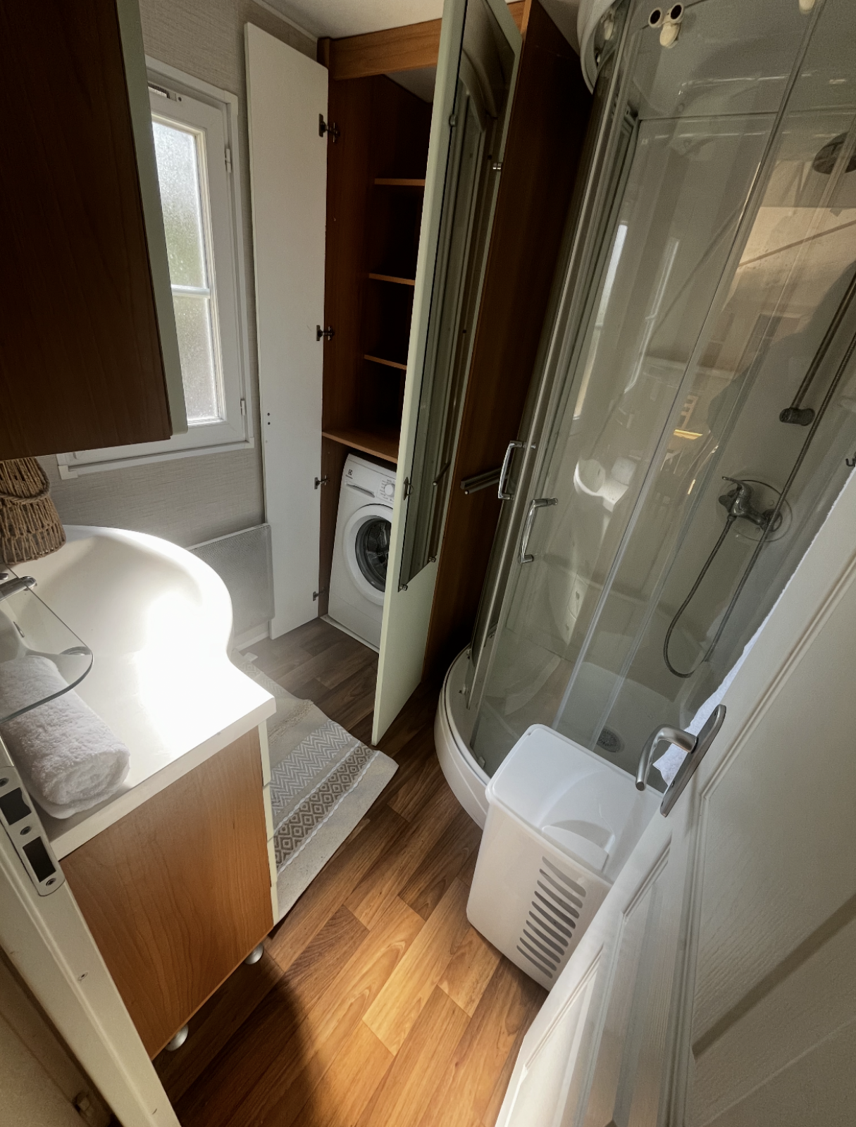 Badkamer in Premium Mobile Home op Camping Les Franquettes, met douchecabine, wasmachine en raam.