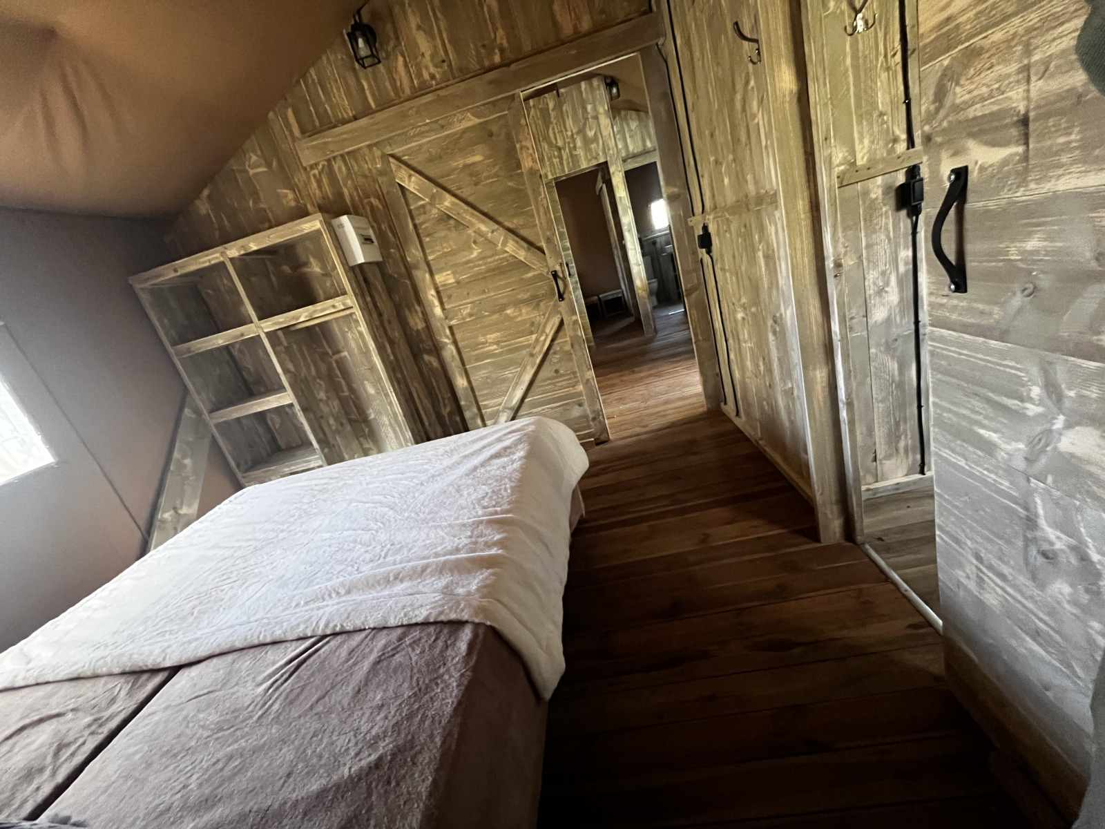 Interieur van een luxe safaritent met houten inrichting op Camping Les Franquettes in Frankrijk.