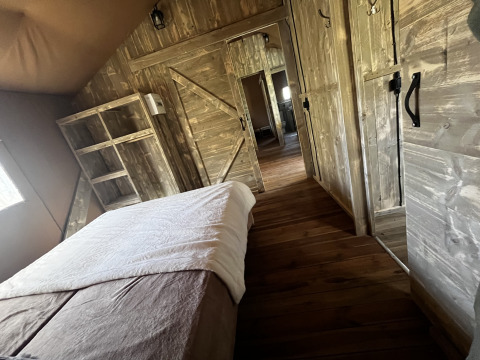 Interieur van een luxe safaritent met houten inrichting op Camping Les Franquettes in Frankrijk.
