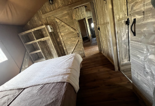 Indvendig udsigt af et luksuriøst safari telt med trædesign hos Les Franquettes Campingplads i Frankrig.