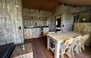 Indretning af Luxury Lodge XXL safari-telt på Camping Les Franquettes i Frankrig med træmøbler.