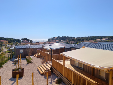View of modern cabins with shaded decks at Campsite Les Tamaris in Provence-Alpes-Côte d’Azur, France, by the sea.