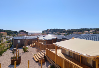 View of modern cabins with shaded decks at Campsite Les Tamaris in Provence-Alpes-Côte d’Azur, France, by the sea.