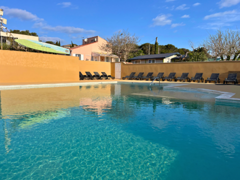 Piscina all’aperto al campeggio Les Tamaris in Provenza-Alpi-Costa Azzurra, Francia, con lettini e cielo sereno.