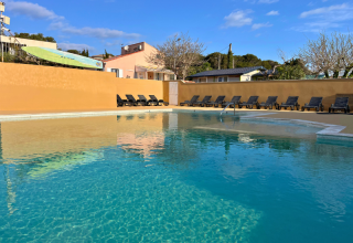 Piscina all’aperto al campeggio Les Tamaris in Provenza-Alpi-Costa Azzurra, Francia, con lettini e cielo sereno.
