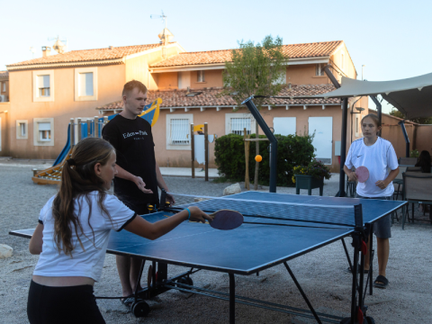 Three people play table tennis outdoors at Campsite Les Tamaris holiday park in Provence-Alpes-Côte d’Azur, France.