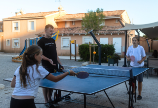 Three people play table tennis outdoors at Campsite Les Tamaris holiday park in Provence-Alpes-Côte d’Azur, France.