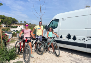 Famiglia con biciclette davanti a un camper bianco al campeggio Les Tamaris, Provenza-Alpi-Costa Azzurra, Francia.