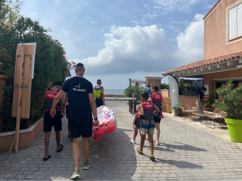 Persone trasportano un kayak lungo un sentiero al campeggio Les Tamaris in Provenza-Alpi-Costa Azzurra, Francia.