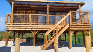 Premium chalet with hilly location, wooden construction raised on stilts with stairs and a terrace.