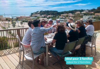 Group enjoying a meal on the terrace at TRIBU mobile homes at Campsite Les Tamaris in France by the sea.