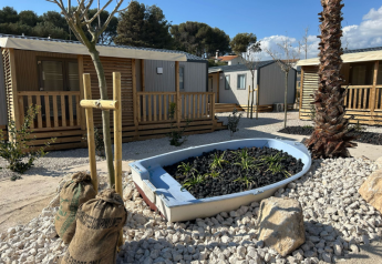 Premium mobile home at Campsite Les Tamaris in France featuring a decorative boat planter and cozy terraces.