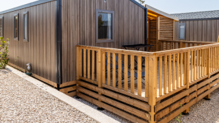 Chalet Premium Mobile Home su posizione collinare, con terrazza in legno e area esterna moderna e luminosa.
