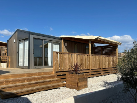 Premium Mobile Home Large: chalet moderno con terrazza in legno e posizione collinare sotto cielo blu.