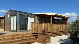 Chalet Premium Mobile Home Large con terraza de madera y ubicación en colina bajo el cielo azul.