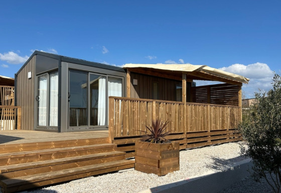 Premium Mobile Home Large: chalet moderno con terrazza in legno e posizione collinare sotto cielo blu.