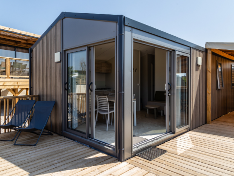 Premium Mobile Home Large Hilly location con arredi moderni, ampio terrazzo e porte scorrevoli in vetro aperte.