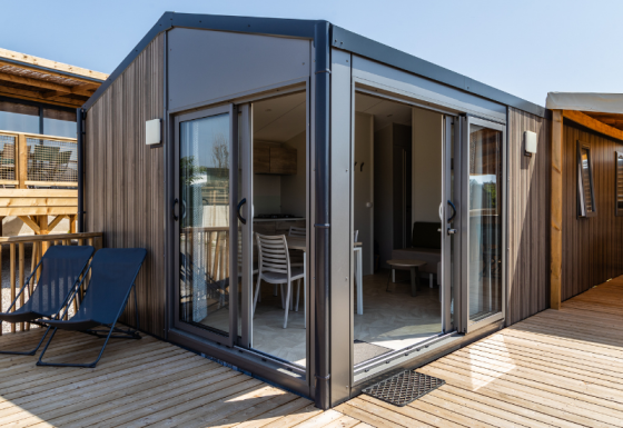 Premium Mobile Home Large Hilly location con arredi moderni, ampio terrazzo e porte scorrevoli in vetro aperte.