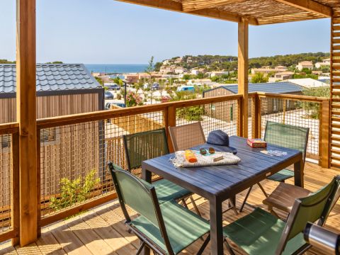 Zicht vanuit een Premium chalet op camping Les Tamaris in Frankrijk, met terras, tafel en uitzicht op zee.