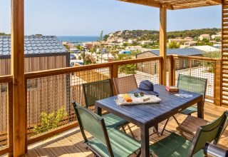 Zicht vanuit een Premium chalet op camping Les Tamaris in Frankrijk, met terras, tafel en uitzicht op zee.