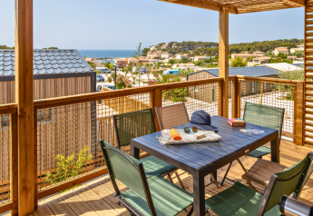 View from Premium chalet at Campsite Les Tamaris, France, showing terrace seating and sea in the background.