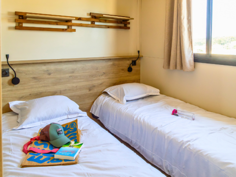 Premium chalet kamer bij Camping Les Tamaris in Frankrijk met twee enkele bedden en ruim raam.
