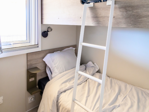Camera chalet moderna con letto singolo, scala a soppalco, finestra luminosa e lampada da parete.