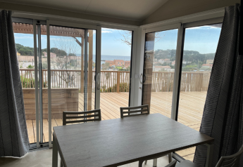 Vue depuis un mobil-home TRIBU au camping Les Tamaris en France, avec terrasse en bois et vue sur la mer.