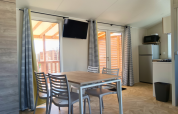 Dining area and kitchenette inside a Premium mobile home at Campsite Les Tamaris in France, modern decor.